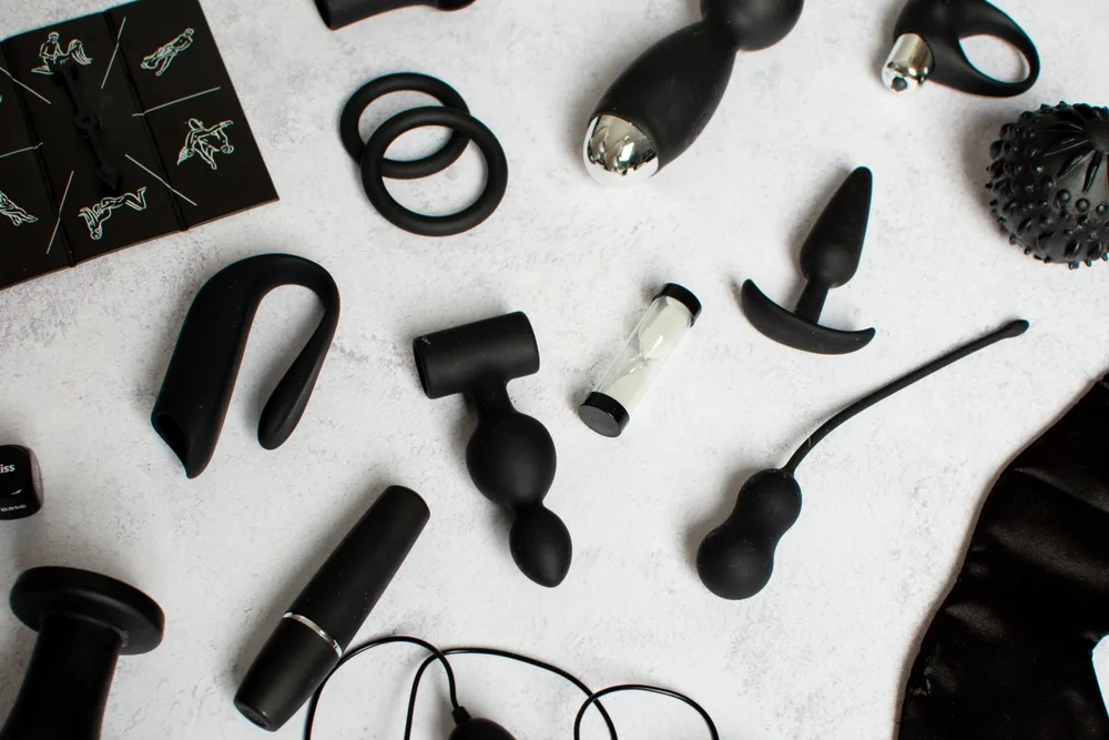 A flat lay of black adult wellness products on a pale surface