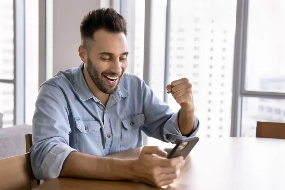 A man celebrating at his phone after a win