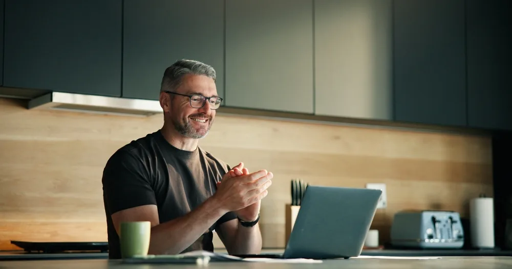 A man celebrating a win at his laptop at home
